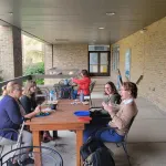 A group seated outside having lunch and chatting.