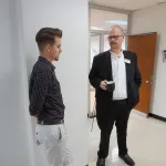 Two people standing, talking.