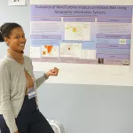 A person posing in front of her poster.