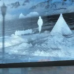 Etched window showing an image of a person and a tent.