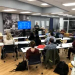 A speaker presenting to an audience in a room. 