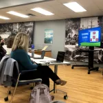 A speaker presenting to an audience in a room. 