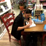 Heidi Roop seated at a table signing books.