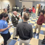 Multiple people discussing a poster in an open space.