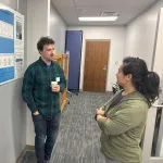  Two people discussing a poster in a hallway.