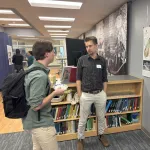 Two people discussing a poster in a library.