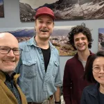 Four people indoors posing for a picture and smiling.