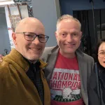 Three people indoors posing for a picture and smiling.