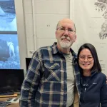 Two people indoors posing for a picture and smiling.