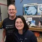 Three people indoors posing for a picture and smiling.