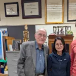 Three people indoors posing for a picture and smiling.