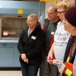 Person giving a presentation to a small group in a laboratory setting.