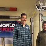 Two individuals standing in front of a poster titled "World First" by the Ice Core Paleoclimatology Group at the Byrd Polar and Climate Research Center, The Ohio State University.