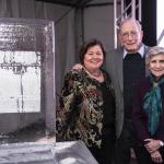 An ice sculpture on a table on the left and Georgie Shockey, Lonnie Thompson and Ellen Mosley Thompson standing next to it with Ellen clutching her arm with one hand while Lonnie is standing in the middle with his hands on both women's shoulders and Georgie resting right hand on the table to her right.
