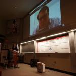 Tom Darrah presenting via Zoom in big screen.