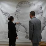Heidi Roop showing Jason Cervenec a location on a very large Antarctic map on the wall.