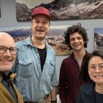 Four people indoors posing for a picture and smiling.