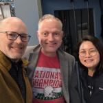 Three people indoors posing for a picture and smiling.