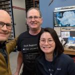Three people indoors posing for a picture and smiling.