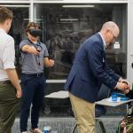 Four people interacting with virtual reality headsets indoors. One individual is being assisted by another to adjust their headset while.